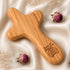 Wooden comfort cross with 'Piece of Holy Land' branding on a soft fabric background with dried flowers.