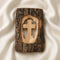 Wooden cross carved into a piece of tree bark on a white fabric background