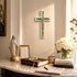 Decorative setup with a cross, statue, books, and flowers on a marble surface.