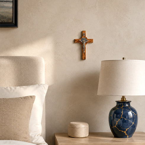 Nursery room with wooden cross on wall, blue marble lamp, and white bedding.