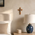 Nursery room with wooden cross on wall, blue marble lamp, and white bedding.