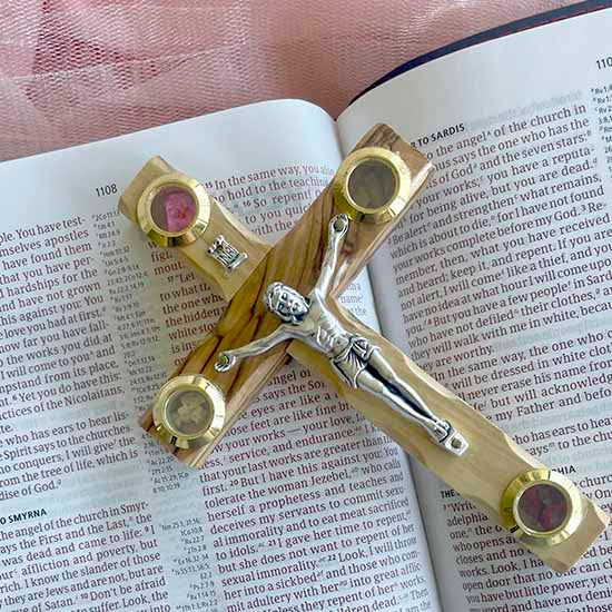 Olive Wood Crucifix Cross with Four Holy Elements laid on an open Bible.