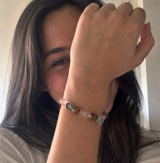 Girl hiding her face with her arm and showing her bracelet