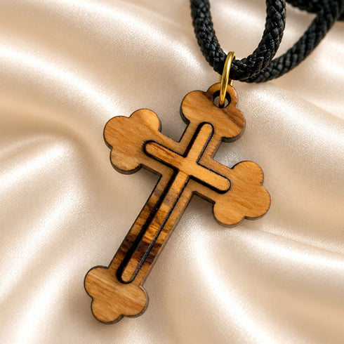Olive wood cross pendant necklace close-up with black cord and gold-tone loop