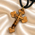 Olive wood cross pendant necklace close-up with black cord and gold-tone loop