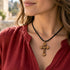 Cross pendant necklace on a woman in red top, black cord and olive wood cross