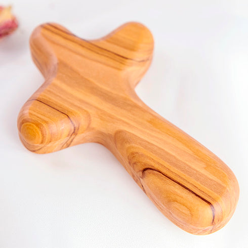 Olive wood comfort cross with the Piece of Holy Land logo, shown on white background with roses