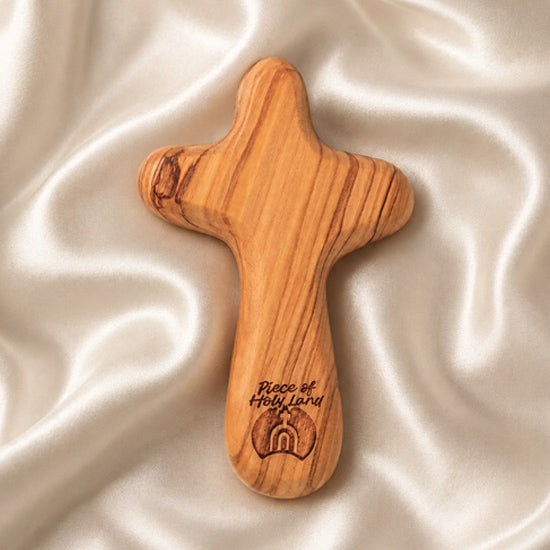 Olive wood comfort cross with the Piece of Holy Land logo on white background .