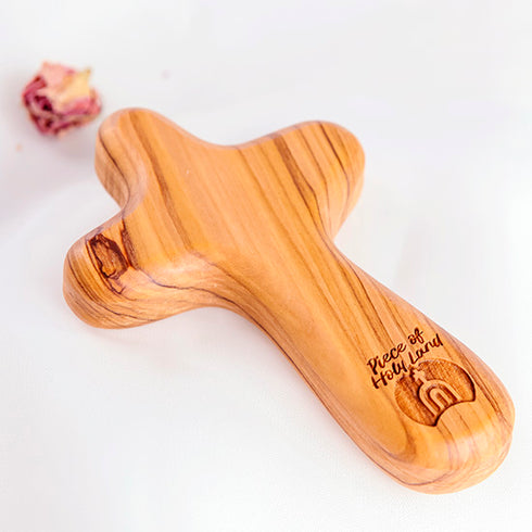 Olive wood comfort cross with the Piece of Holy Land logo, shown on white background with roses