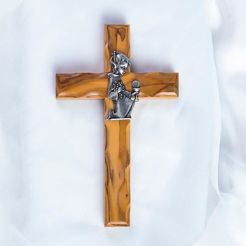 A handcrafted olive wood communion cross with a metal emblem of a praying girl on it.