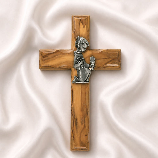 A handcrafted olive wood communion cross with a metal emblem of a praying girl on it.