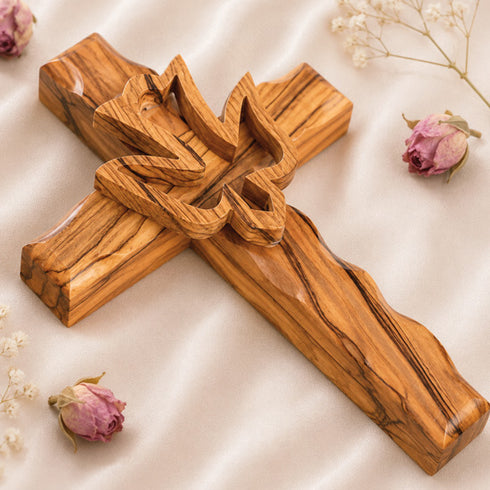 Handcrafted olive wood cross featuring an embossed dove motif, set against a white background with rose buds.