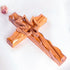 Pack shot image of a handcrafted olive wood cross featuring an embossed dove motif, set against a white background with a petal.