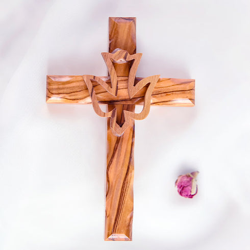 Frontal image of a handcrafted olive wood cross featuring an embossed dove motif, set against a white background with a petal.