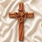 Frontal image of a handcrafted olive wood cross featuring an embossed dove motif, set against a white background.