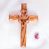 Frontal image of a handcrafted olive wood cross featuring an embossed dove motif, set against a white background with a petal.