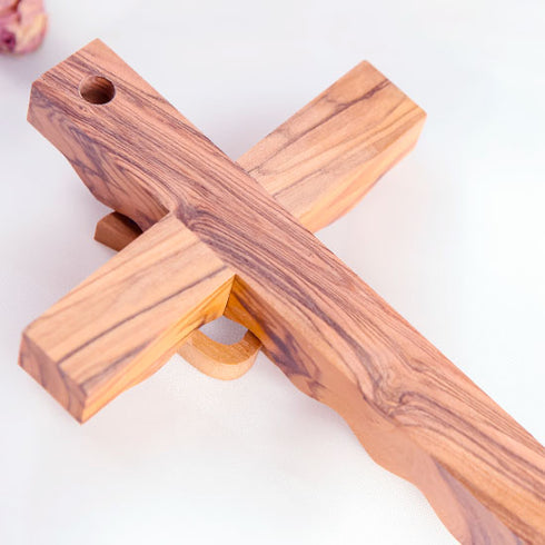 Back of a handcrafted olive wood cross featuring an embossed dove motif, set against a white background.