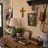 Nook with wooden dresser, lamp, cross, and various items on a wall.