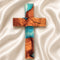 Wooden cross with blue and brown resin on a white fabric background