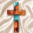 Wooden cross with blue and brown resin on a white fabric background