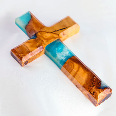 Image of a handcrafted olive wood cross with blue and green epoxy, polished and displayed on a white background.