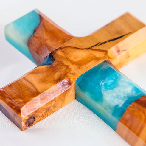 Image of a handcrafted olive wood cross with blue and green epoxy, polished and displayed on a white background.