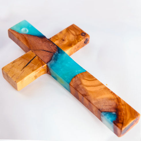 Image of a handcrafted olive wood cross with blue and green epoxy, polished and displayed on a white background.