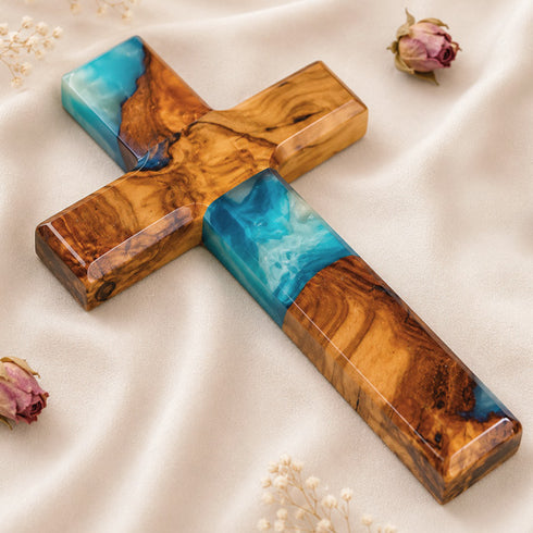 Image of a handcrafted olive wood cross with blue and green epoxy, polished and displayed on a white background.
