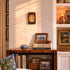 Nestled corner of a room with a wooden shelf displaying books, decorative items, and framed photos.