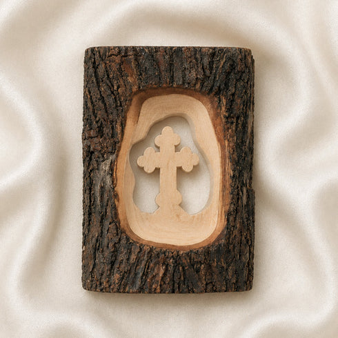 Pack shot of a standing olive wood cross handmade of natural bark, placed on a golden cloth.