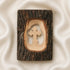 Pack shot of a standing olive wood cross handmade of natural bark, placed on a golden cloth.