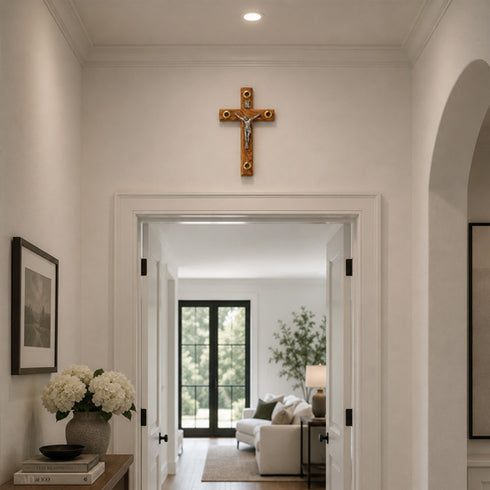 Decorative cross on a wall above an open door leading to a living room.