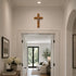Decorative cross on a wall above an open door leading to a living room.
