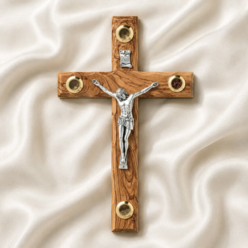 Wooden cross with a silver figure of Jesus on a white fabric background