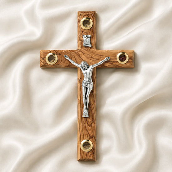 Wooden cross with a silver figure of Jesus on a white fabric background