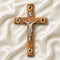 Wooden cross with a silver figure of Jesus on a white fabric background