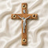 Wooden cross with a silver figure of Jesus on a white fabric background