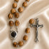 A handmade olive wood rosary with an iron crucifix, featuring a holy soil container centrepiece.