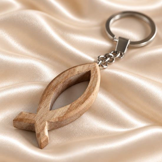 Olive wood Ichthys fish keyholder with Christian fish symbol and metal key ring on a neutral background