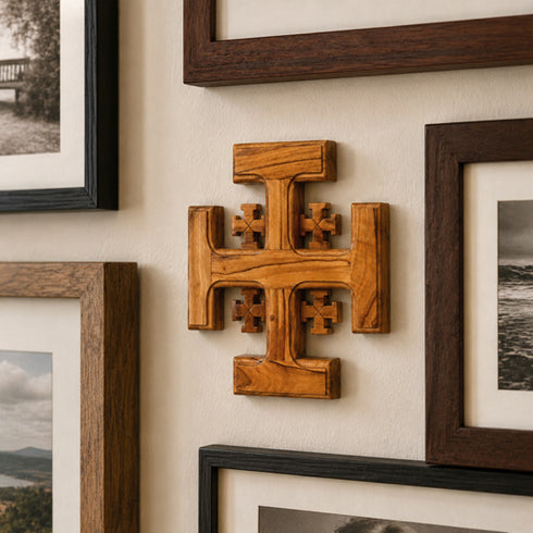 Wooden cross wall art with framed photographs on a wall