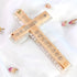 Back of a Latin-style olive wood cross with "Jerusalem" and the Stations of Cross written on it, against white background with rose petals around it.