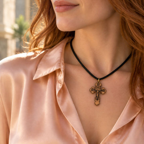 Olive-wood cross pendant necklace on black cord, worn at the neckline