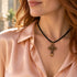 Olive-wood cross pendant necklace on black cord, worn at the neckline