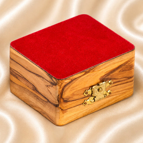 Bottom of an olive wood box with red cloth, placed on satin beige background.