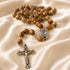 Olive wood rosary with Holy Water centerpiece on a creamy color cloth.