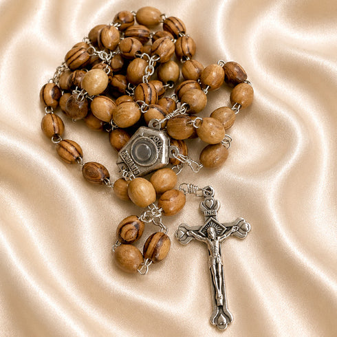 Olive wood rosary with Holy Water centerpiece and apostile cross on a creamy color cloth.