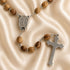 Close up of an olive wood rosary with Holy Water centerpiece on a creamy cloth.