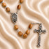 Close up of Olive wood rosary centerpiece and the cross on a creamy color cloth.
