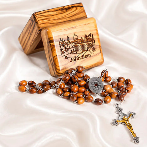 Wooden rosary with Jerusalem design on a wooden box on a white fabric background