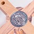 Detail of a back of a handmade olive wood cross with a blue St. Benedict medallion on a white background.